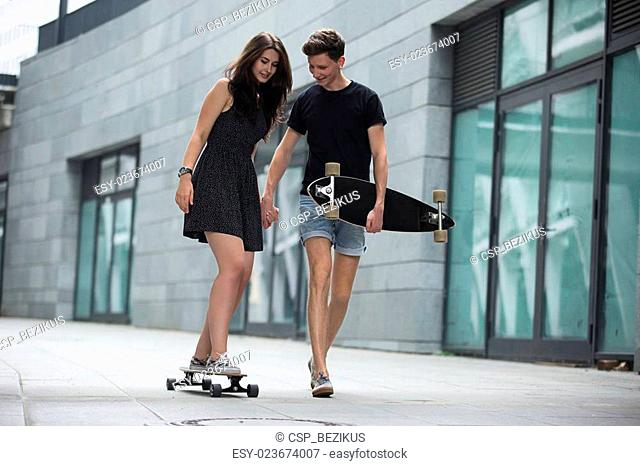 Young pair in love of stylish teenagers ride longboards