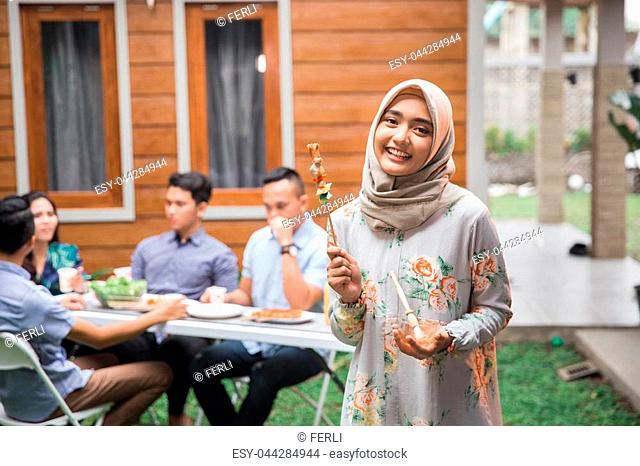 Portrait of a young pretty girl holding shashlik smiling through the camera. barbecue with friends