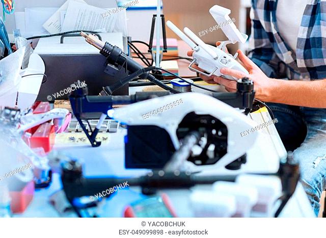 Solve the problem. Close up of hardworking mans hands repairing details of drone while holding them and using soldering iron