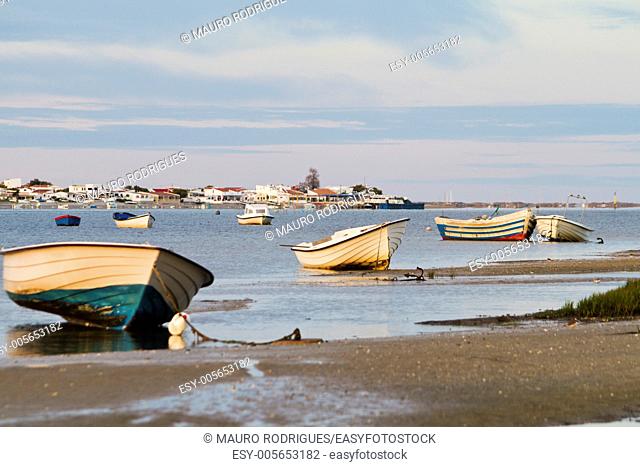 Beautiful view of sunrise with a beach and small fishing boats near Olhao, Portugal