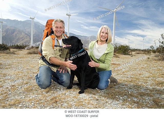 Senior couple with dog near wind farm
