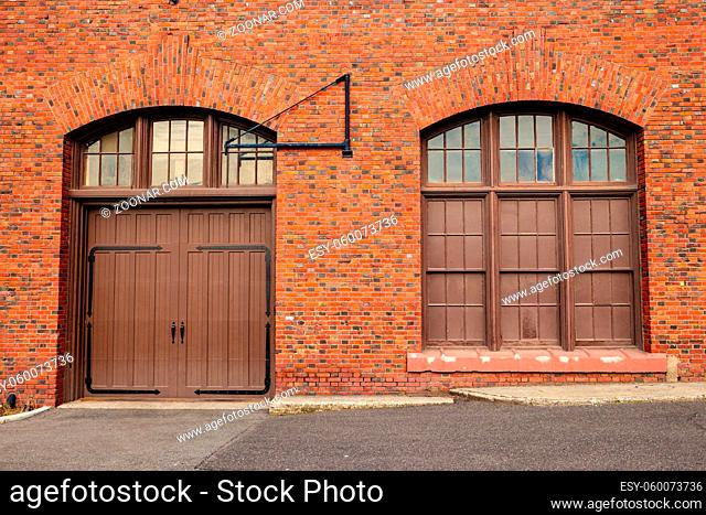 A large door and window on the side of a old red bricked building