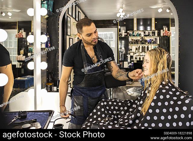 Stylist sitting young woman in chair after washing hair preparing for haircut at boutique salon