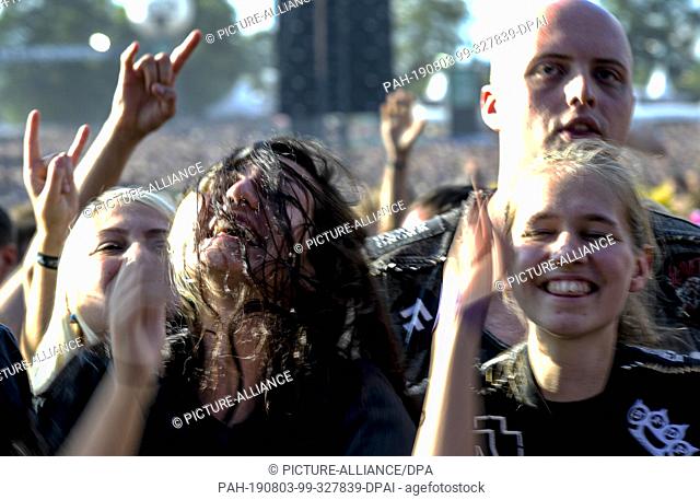 03 August 2019, Schleswig-Holstein, Wacken: Festival participants of the WOA (Wacken Open Air) celebrate in front of one of the stages