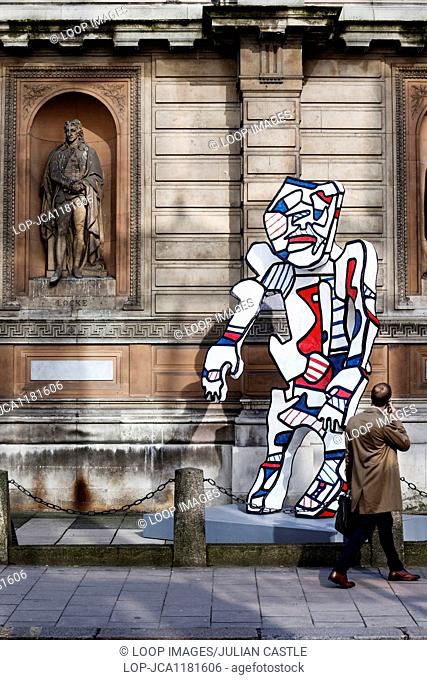 A businessman turns to view an art installation outside the Royal Academy of Arts in London