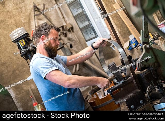 03 September 2020, Bremen: In his barrel factory, barrel maker Christoph Krogemann prepares a barrel hoop for the tiring of a barrel