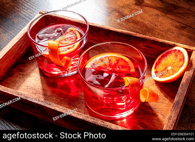 Negroni cocktails with ice and blood oranges on a dark wooden background