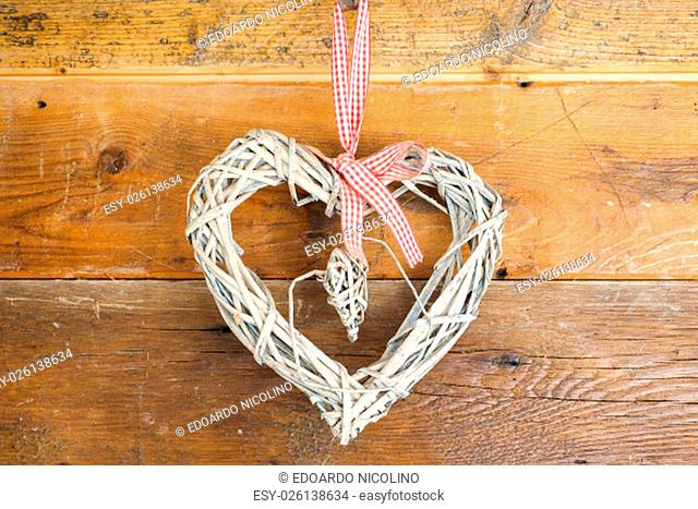 Home made heart built with straw, hanged to wooden wall to celebrate Saint Valentine day