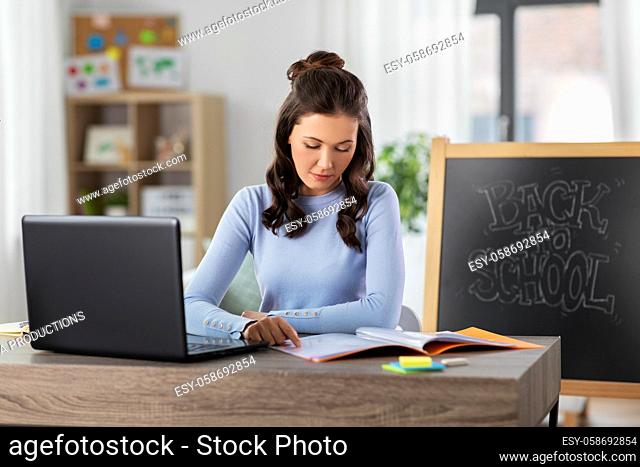 teacher with laptop and notebook working from home