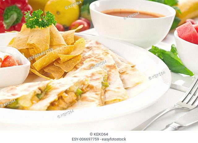 original Mexican quesadilla de pollo with nachos served with gazpacho soup and watermelon , with fresh vegetables on background
