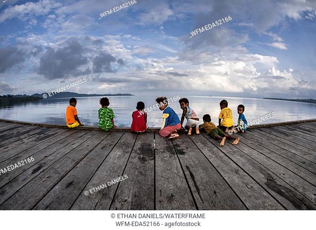 Papuan children play on village dock, Raja Ampat, West Papua, Indonesia
