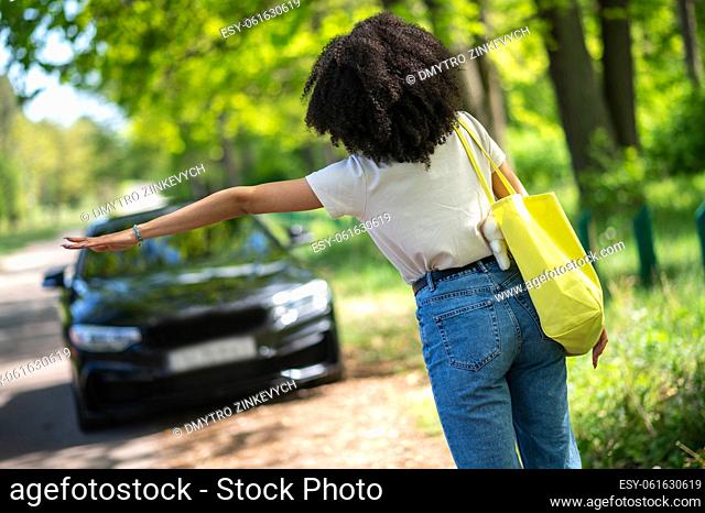 Hitchhiking. Curly-haired young girl hitchhiking and looking excited