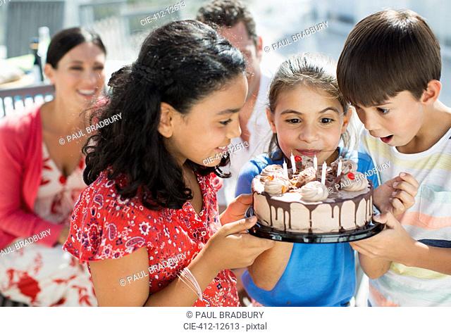 Children holding birthday cake outdoors