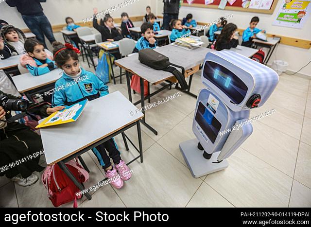 02 December 2021, Palestinian Territories, Gaza City: Palestinian students interact with a home-made talking educational robot during a science class at a...