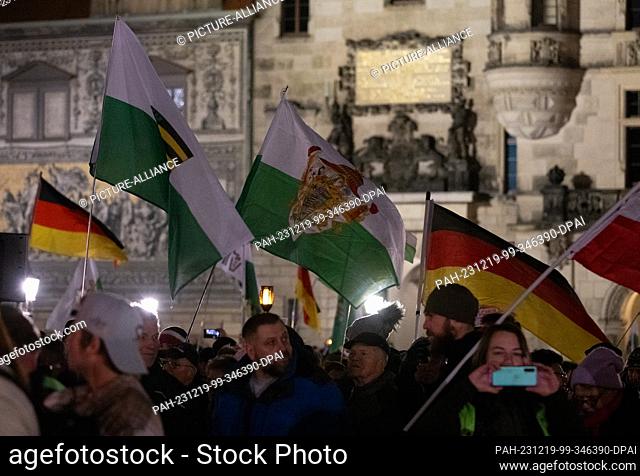 18 December 2023, Saxony, Dresden: Participants in a demonstration by the right-wing extremist movement Pegida walk across the Augustus Bridge in the evening