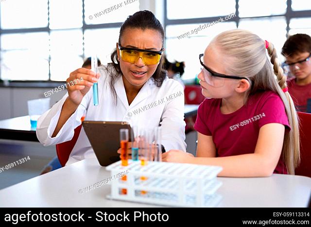 African american female teacher teaching chemistry to a girl during science class at laboratory