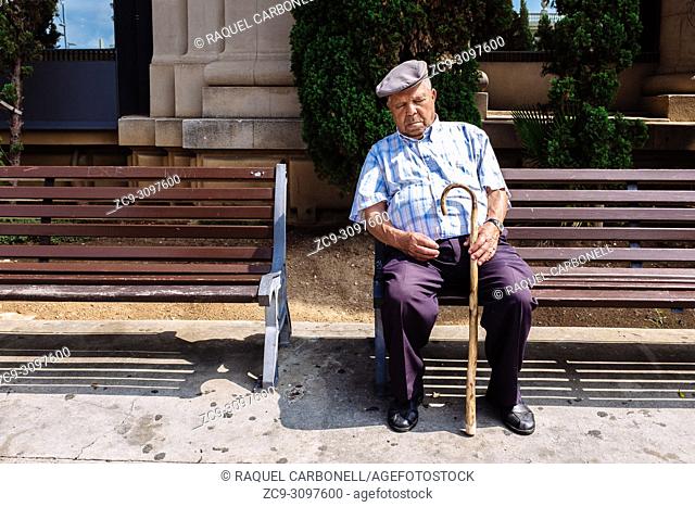 Old men wearing a typical beret sleeping while sitting on a public bench, Barcelona, Catalonia, Spain
