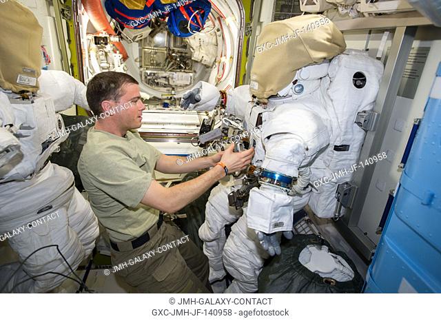 NASA astronaut Reid Wiseman, Expedition 41 flight engineer, works with tools and equipment on an Extravehicular Mobility Unit (EMU) spacesuit in the Quest...