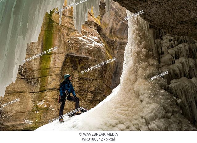 Male climber standing near rocky ice mountain