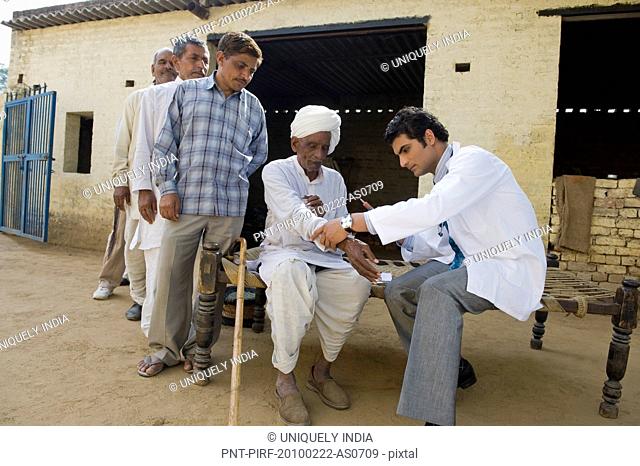 Doctor giving an injection to a farmer, Hasanpur, Haryana, India