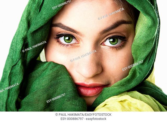 Portrait of mysterious beautiful Caucasian Hispanic Latina woman face with green penetrating eyes and green fashion scarf wrapped around head, isolated