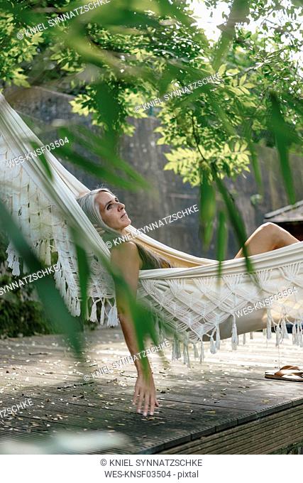 Pensive woman relaxing in hammock in the garden