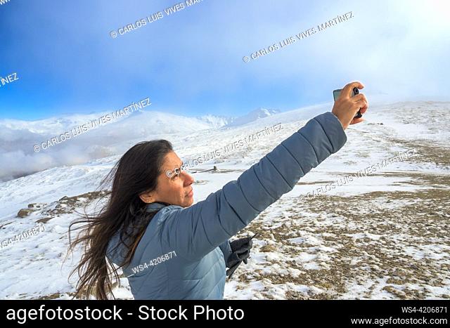 Latina woman taking a selfie with a smartphone while enjoying a winter day in sierra nevada, granada,