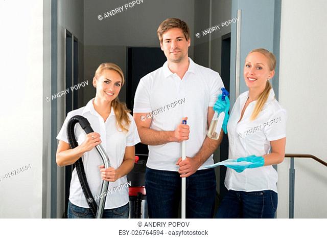 Group Of Happy Young Janitors Holding Cleaning Equipments