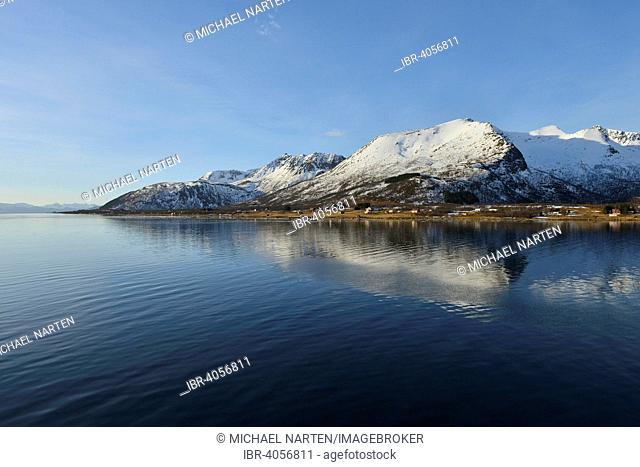Snow-capped mountains of the southern island of Andøya reflected in Risøysund, Andøya, Vesteralen, Norway