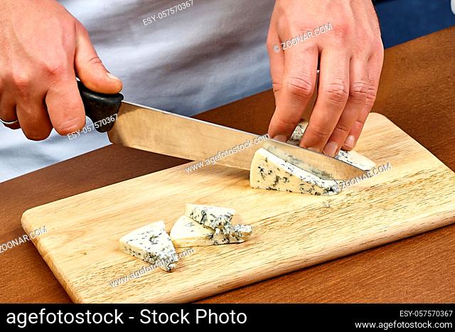 cutting cheese on a wooden cooking board male hands chef