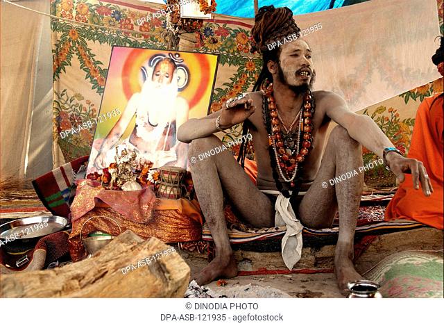 A naga sadhu from the Juna Akadha sits with his Trishul at their camp during the Ardh Kumbh Mela , , , India