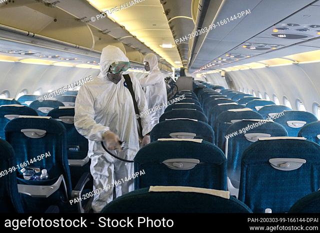 03 March 2020, Vietnam, Hanoi: Members of staff of the Center for Disease Control in Hanoi spray disinfectant inside a plane at Noi Bai International Airport...