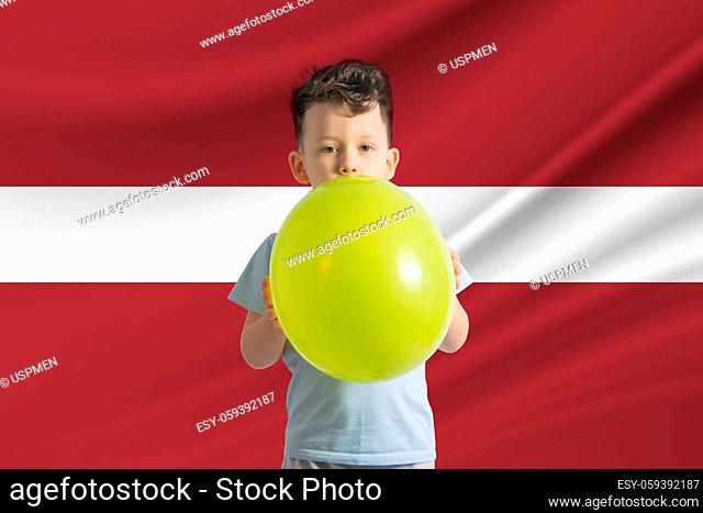 Children's day in Latvia White boy with a balloon on the background of the flag of Latvia Childrens day celebration concept