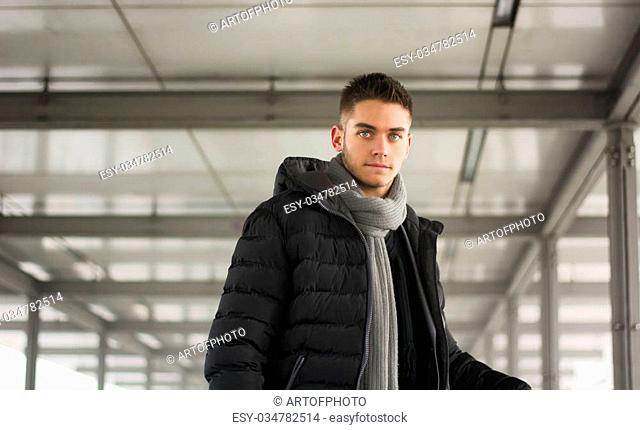 Attractive young man under tunnel in urban environment, looking at camera, wearing winter clothing