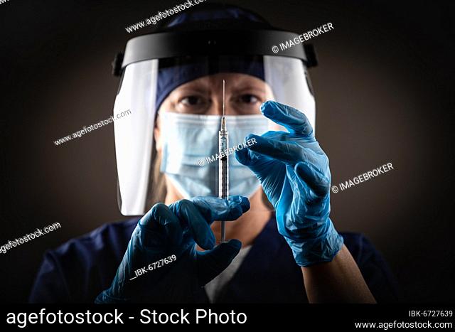 Doctor or nurse holding medical syringe with needle against dark background