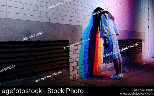 Stressed woman leaning head on wall at night