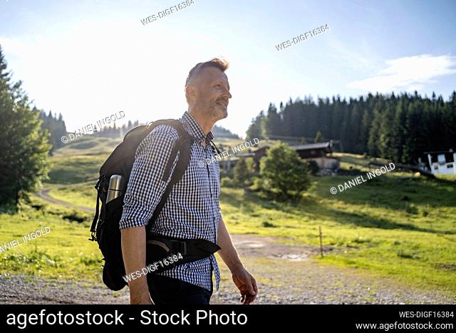 Smiling male backpacker hiking on sunny day