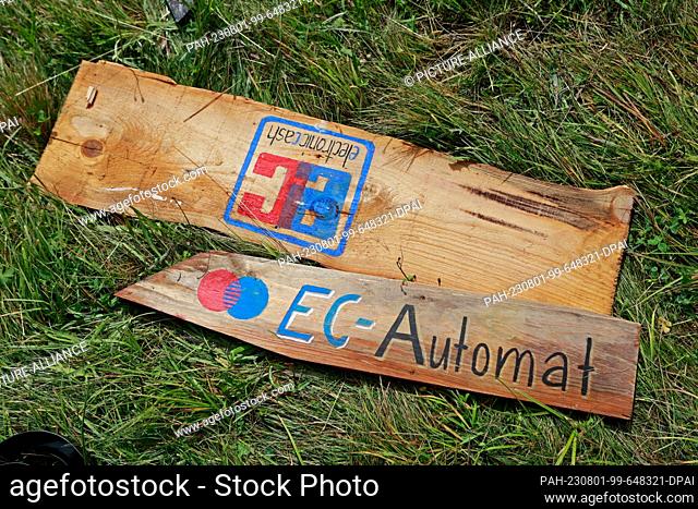 01 August 2023, Saxony-Anhalt, Elend: Signs to the EC machine and eletronic cash lie on a festival meadow in Elend . For the festival ""Rocken am Brocken""