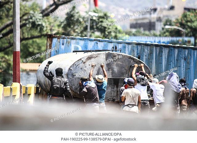 25 February 2019, Colombia, Cucuta: Demonstrators are trying to get the trailer of a tanker truck that is blocking the Simon Bolivar bridge on the border...