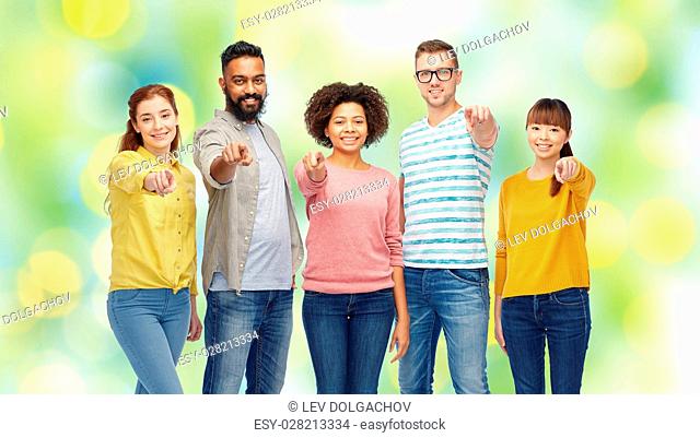 diversity, race, ethnicity and people concept - international group of happy smiling men and women pointing finger on you over green holidays lights background