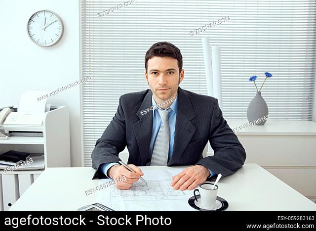 Young architect working at office desk, smiling