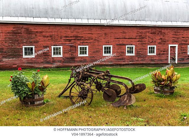 Close up of a red barn and a historic plough in North Randolph, Vermont, USA