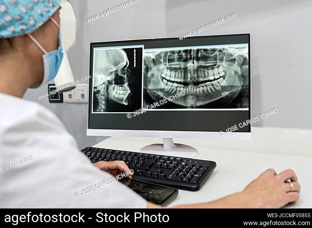 Dentist examining x-ray image on computer at medical clinic