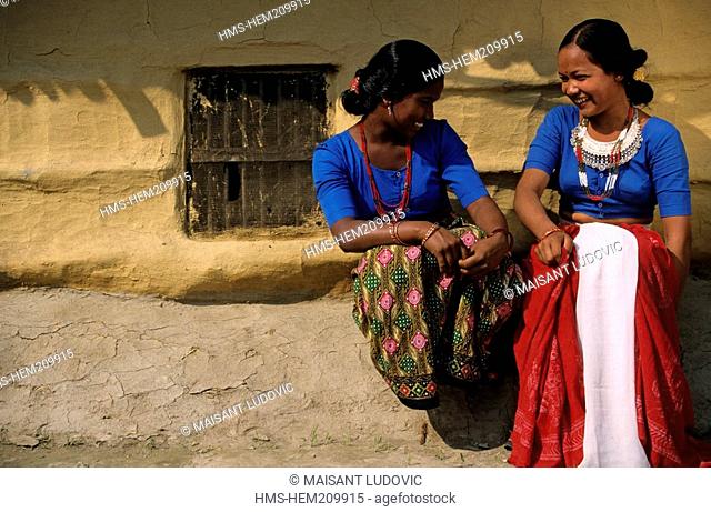 Nepal, the Terai Madhesh, Royal Bardia National Park, a Tharu village, young girls in front of a traditional house
