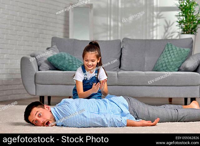 happy little child daughter doing massage to father at home. Father's day