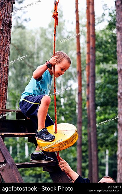 Happy boy getting in the zip line in rope park in forest while spending summer vacation. Real people, authentic situations