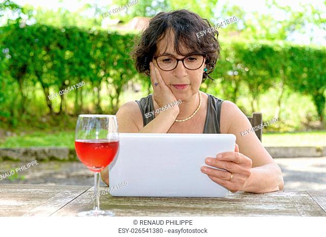 a charming woman with a tablet in her garden