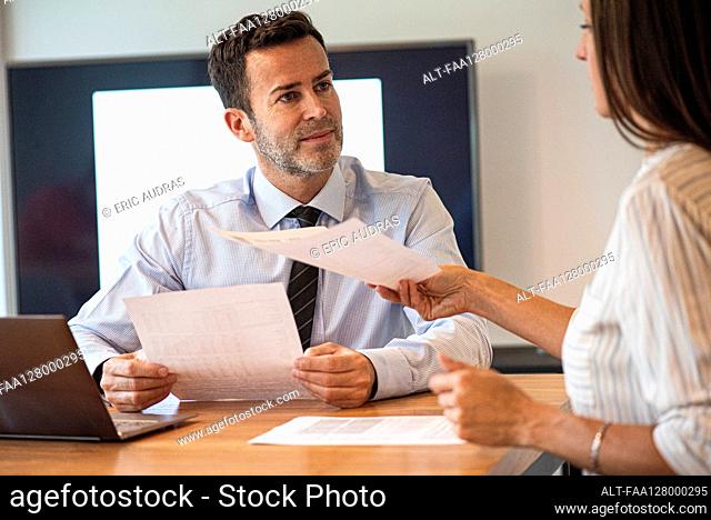 Businesswoman passing a document to a businessman
