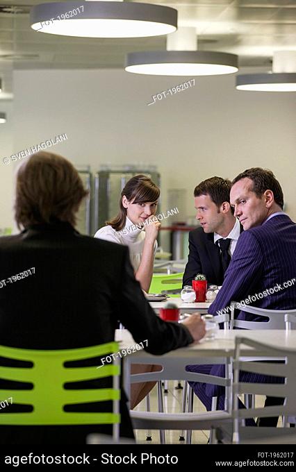 Business people gossiping about colleague in office cafeteria