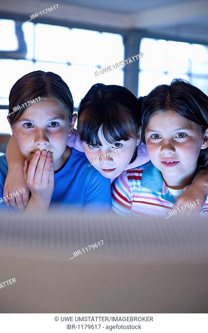 Three girls looking anxiously at a screen